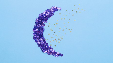 Photo of Beautiful sequins in shape of moon and stars on light blue background, flat lay