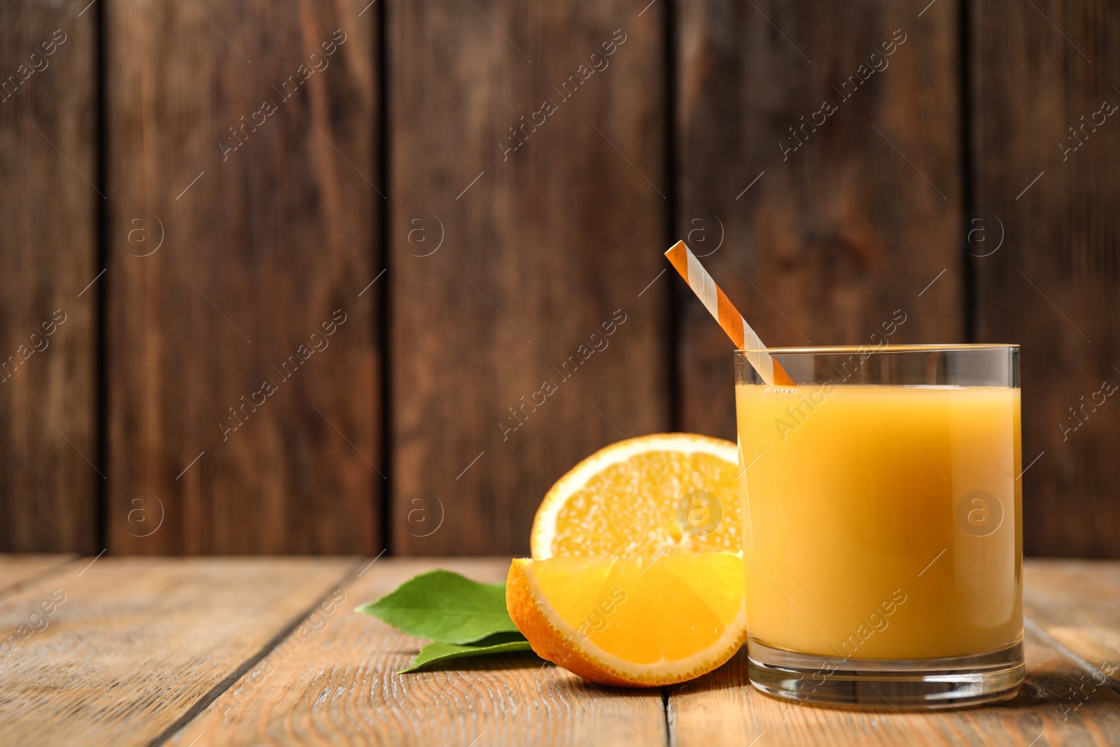 Photo of Glass of orange juice and fresh fruits on wooden table. Space for text