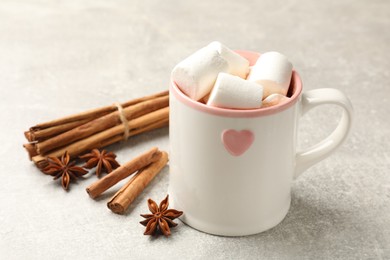 Photo of Tasty hot chocolate with marshmallows and spices on light grey table, closeup