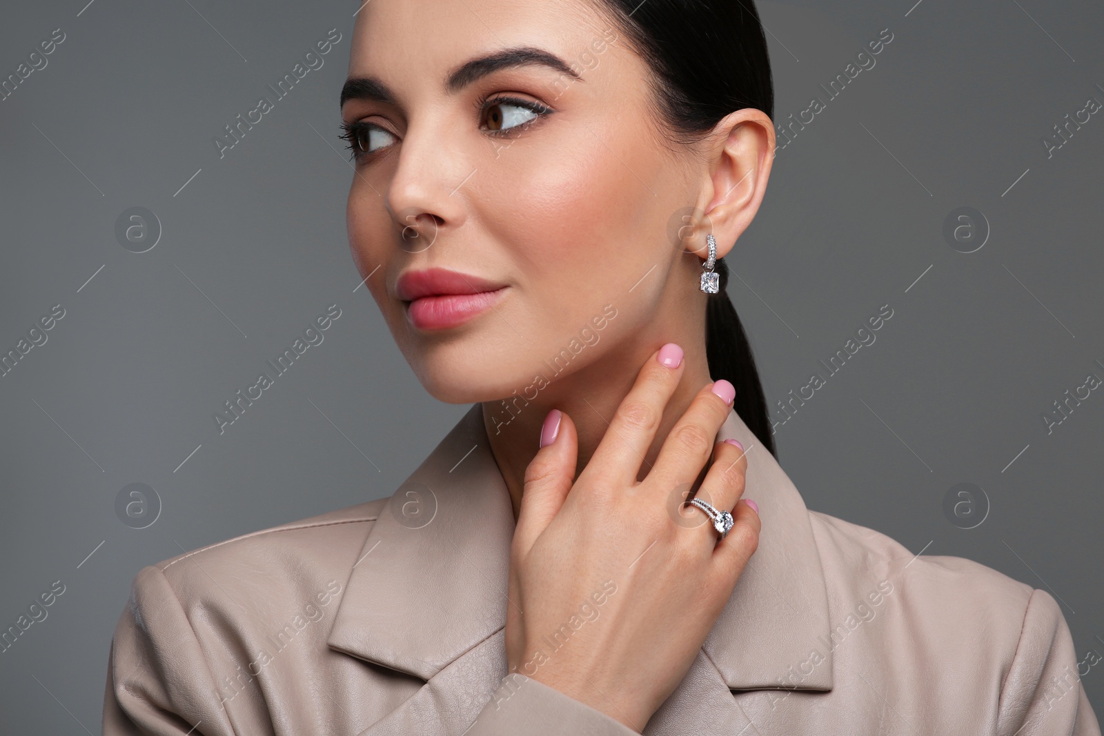 Photo of Young woman with elegant jewelry on dark grey background, closeup