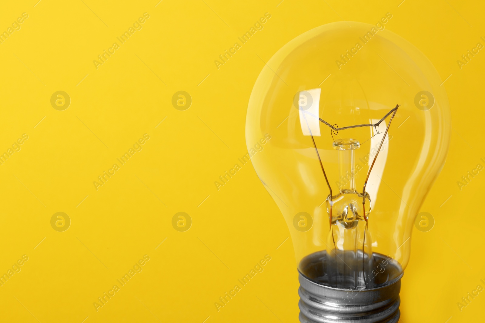 Photo of New modern lamp bulb on yellow background, space for text