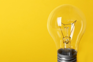 New modern lamp bulb on yellow background, space for text