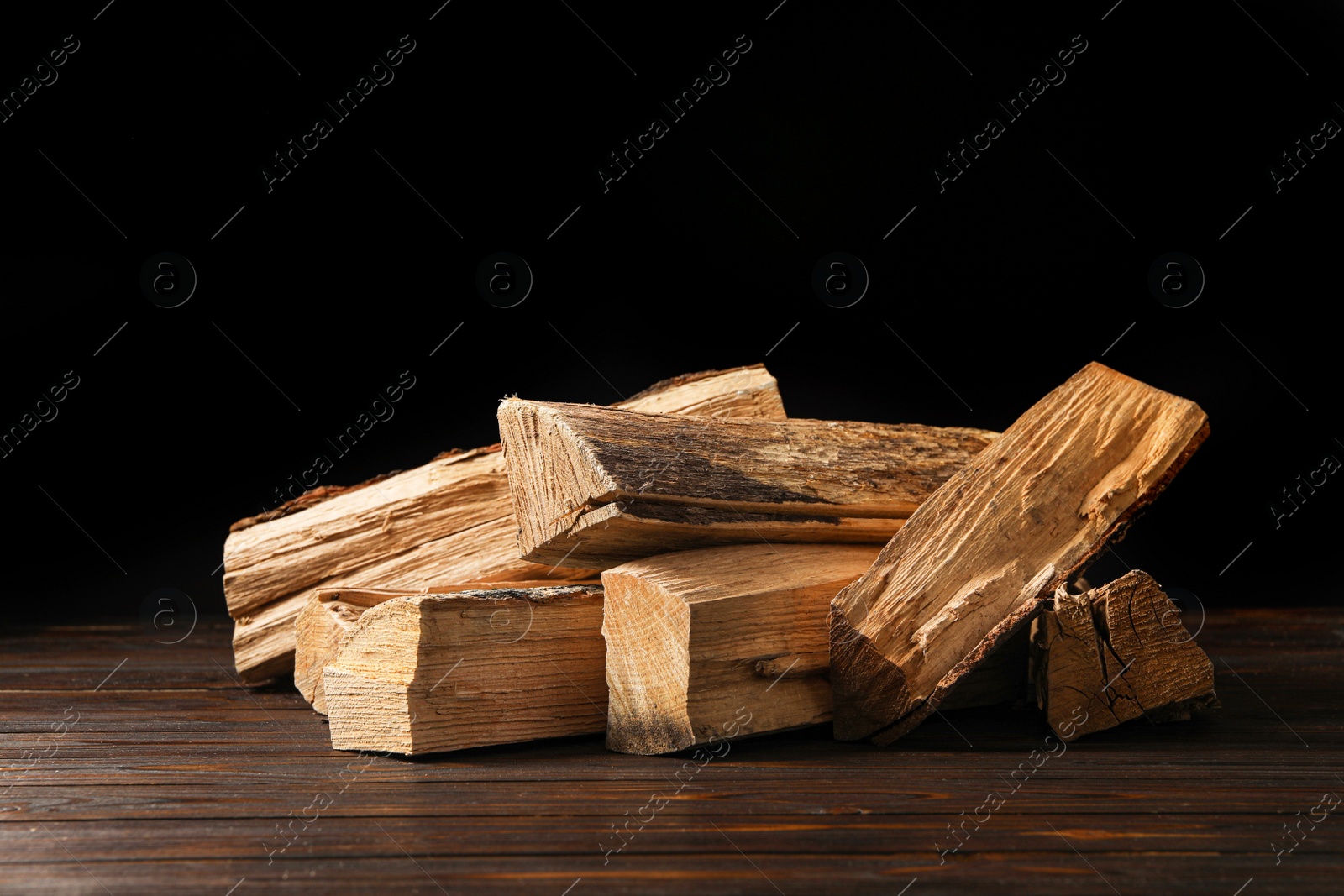 Photo of Cut firewood on table against black background