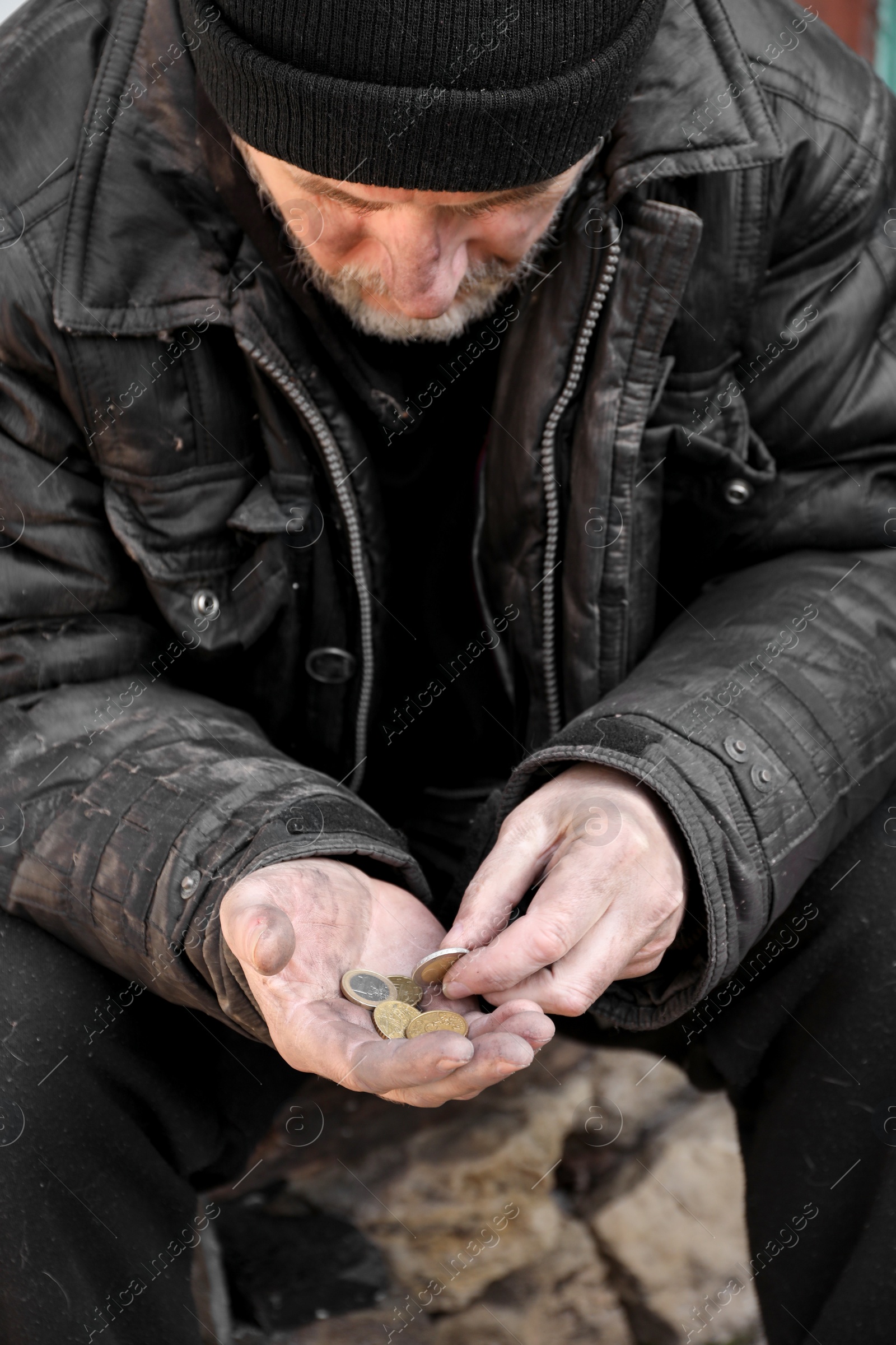 Photo of Poor homeless senior man holding coins outdoors