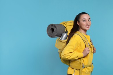 Photo of Smiling young woman with backpack on light blue background, space for text. Active tourism