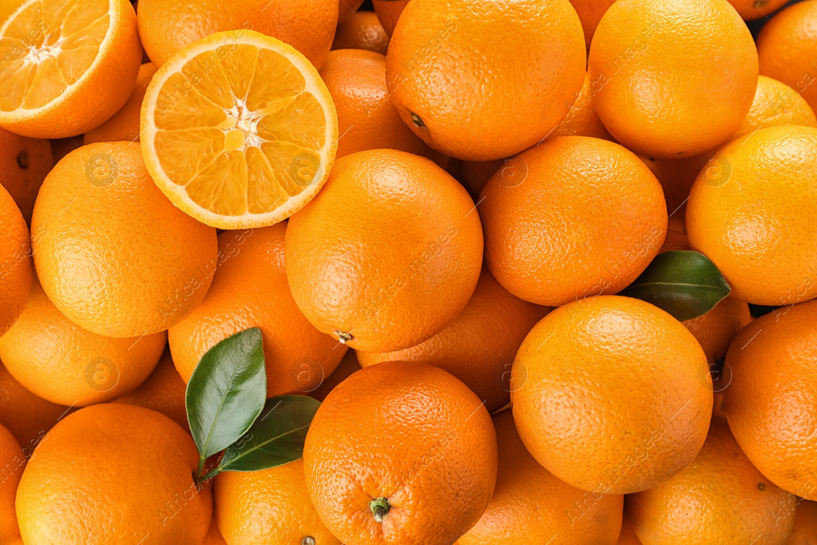 Photo of Pile of fresh ripe oranges with leaves as background, top view