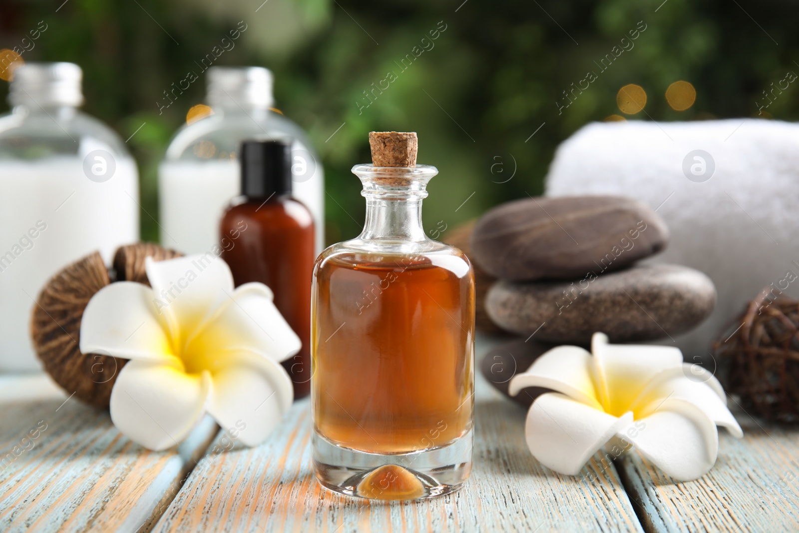 Photo of Composition with spa cosmetic and plumeria flowers on light wooden table, closeup