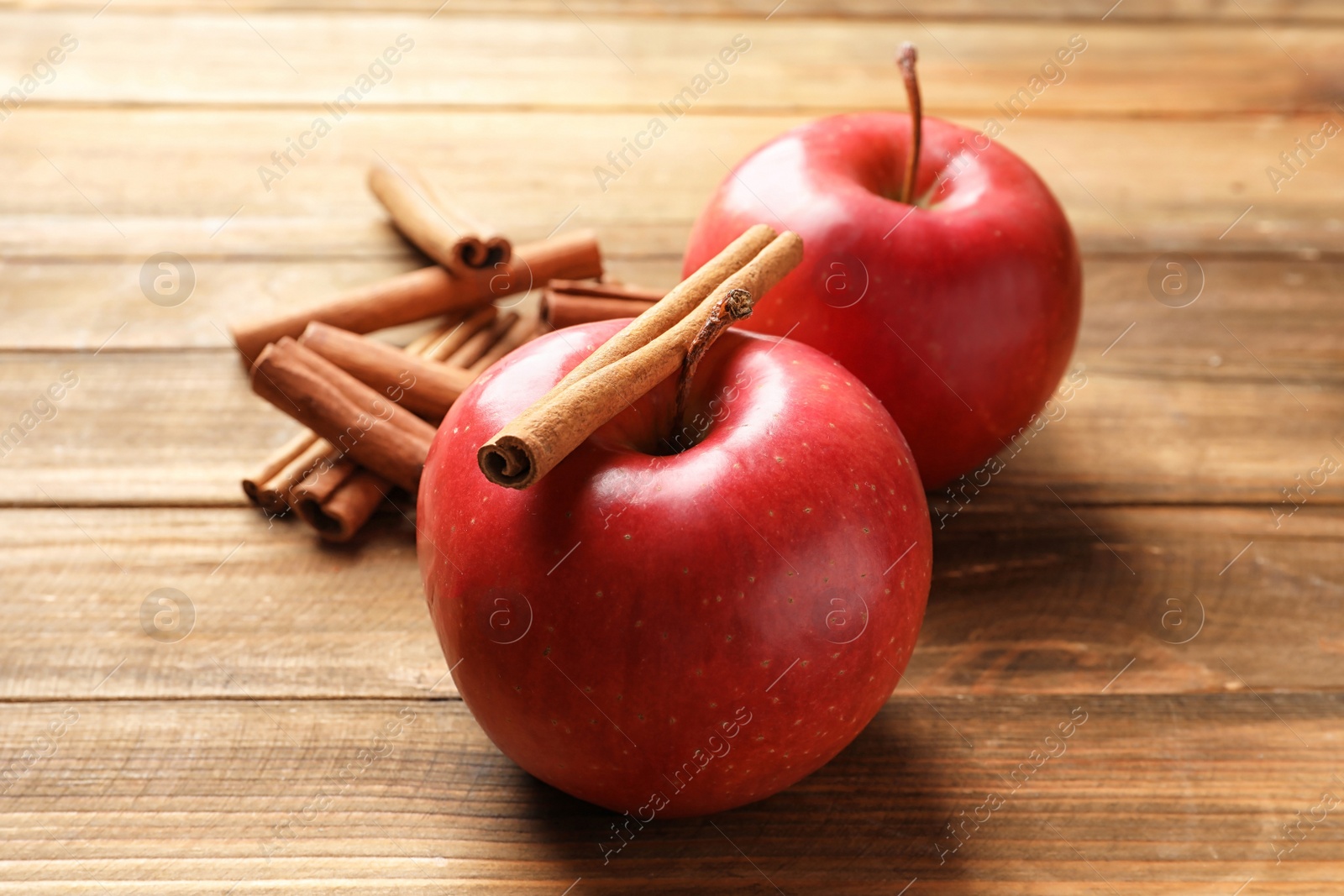 Photo of Fresh apples and cinnamon sticks on wooden table