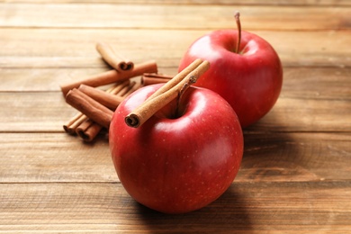 Photo of Fresh apples and cinnamon sticks on wooden table