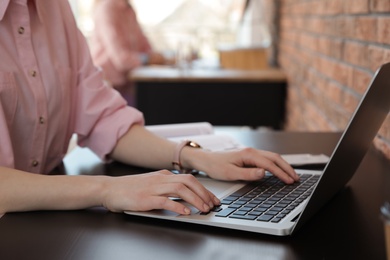 Photo of Young businesswoman using laptop at table in office, closeup