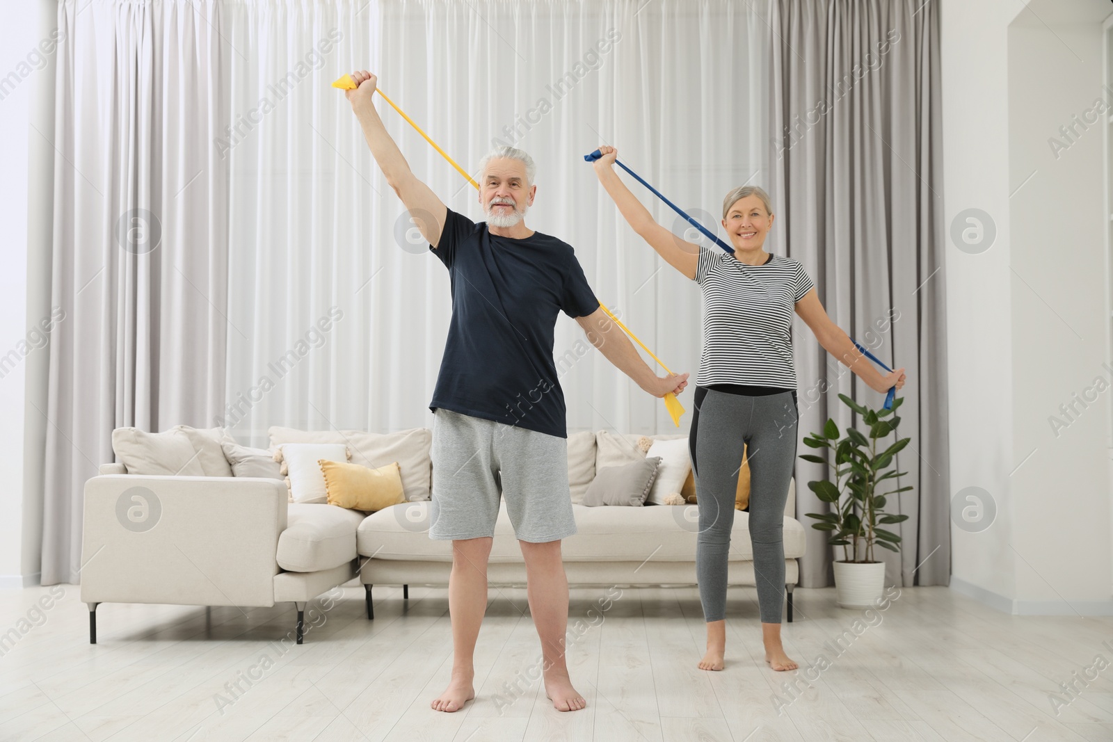 Photo of Senior couple doing exercise with fitness elastic bands at home