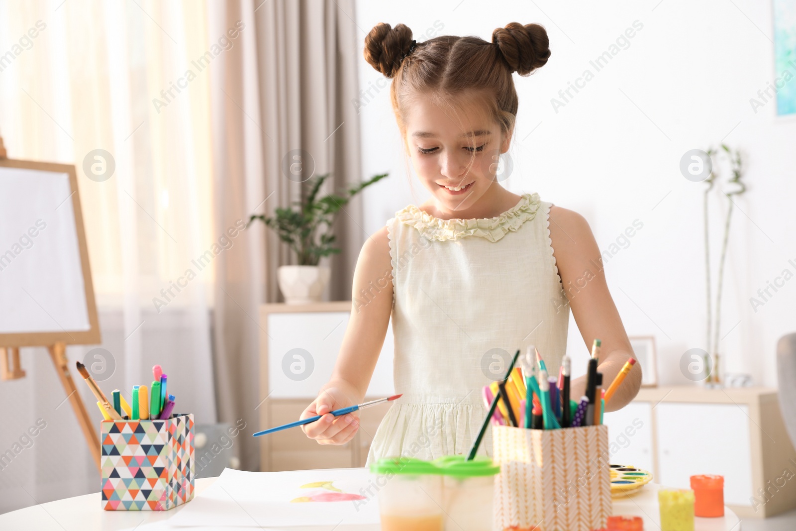 Photo of Little girl painting picture at table indoors