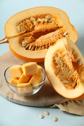 Photo of Cut fresh ripe pumpkin on light blue background, closeup