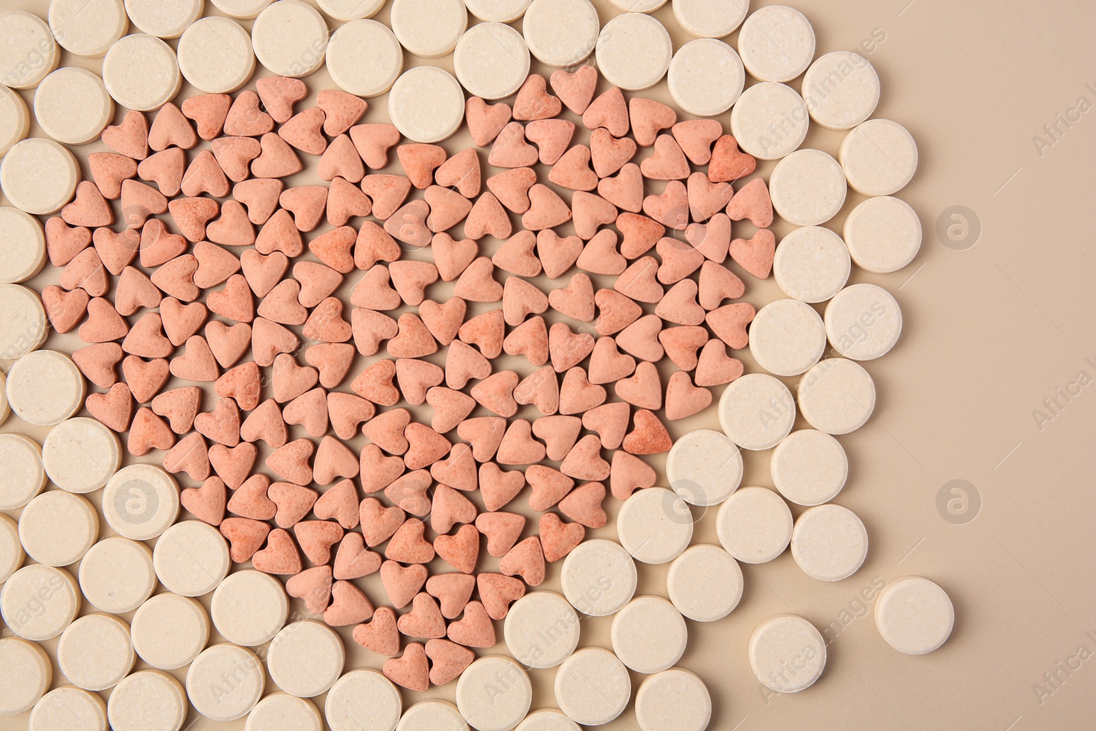 Photo of Heart made of vitamins for pets on beige background, flat lay