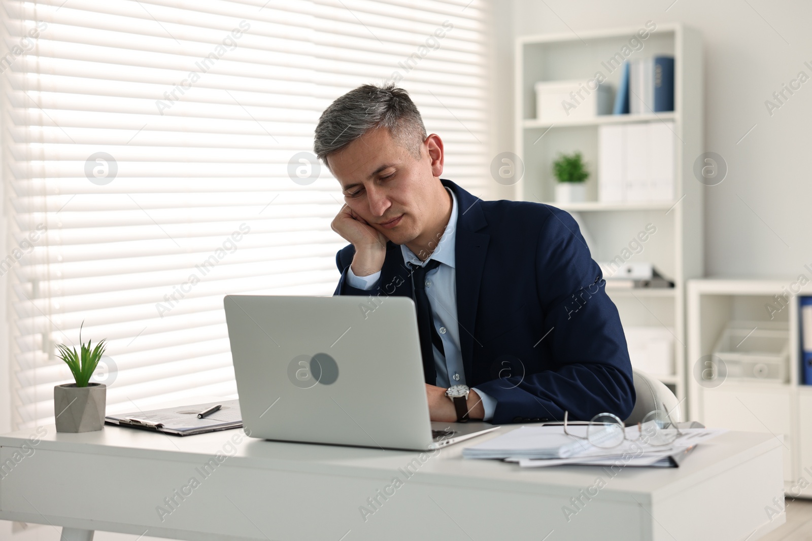 Photo of Sleepy man at table with laptop in office