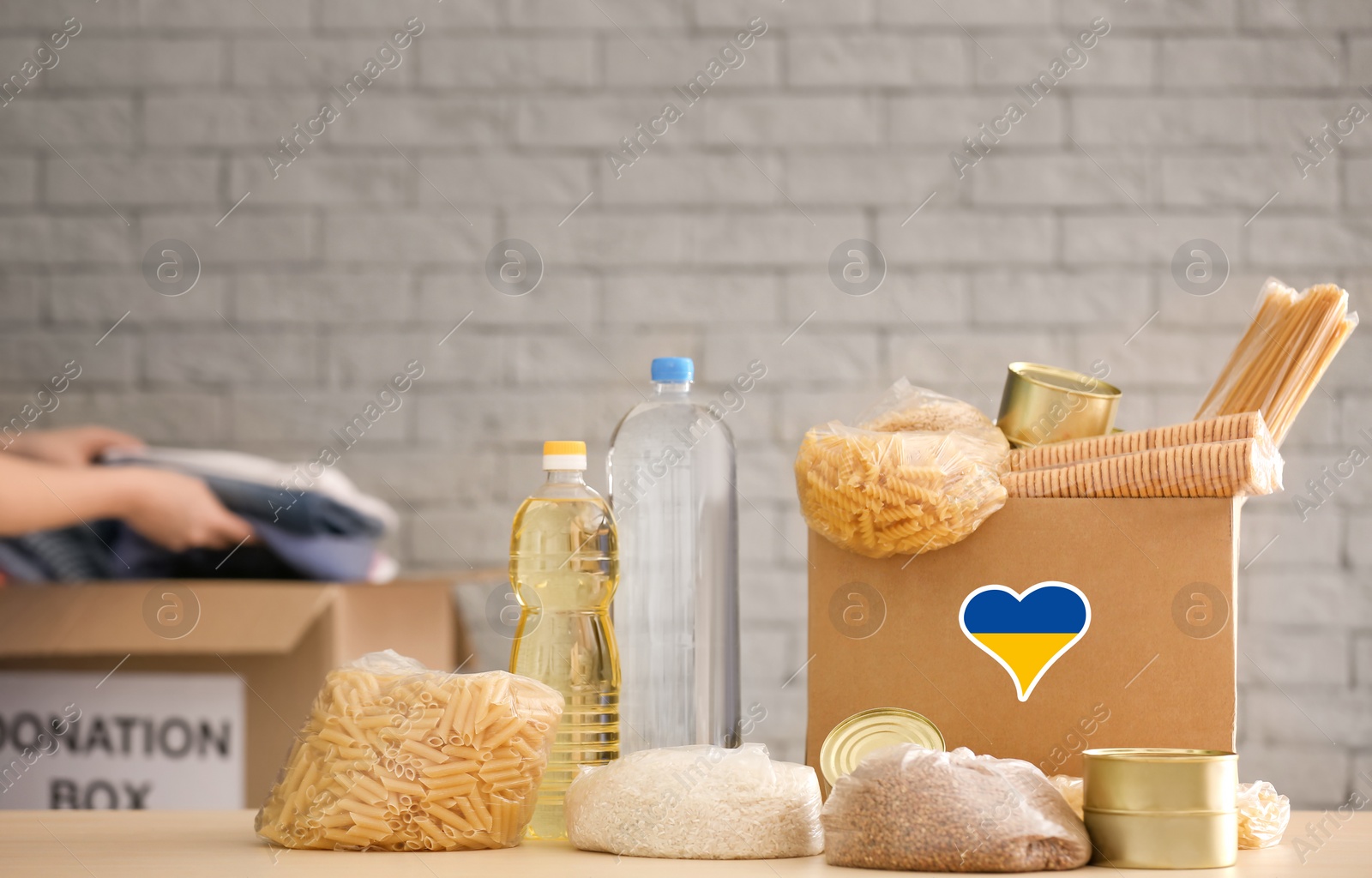 Image of Humanitarian aid for Ukrainian refugees. Donation box with food on table against brick wall