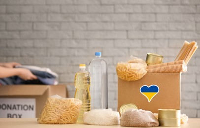 Image of Humanitarian aid for Ukrainian refugees. Donation box with food on table against brick wall