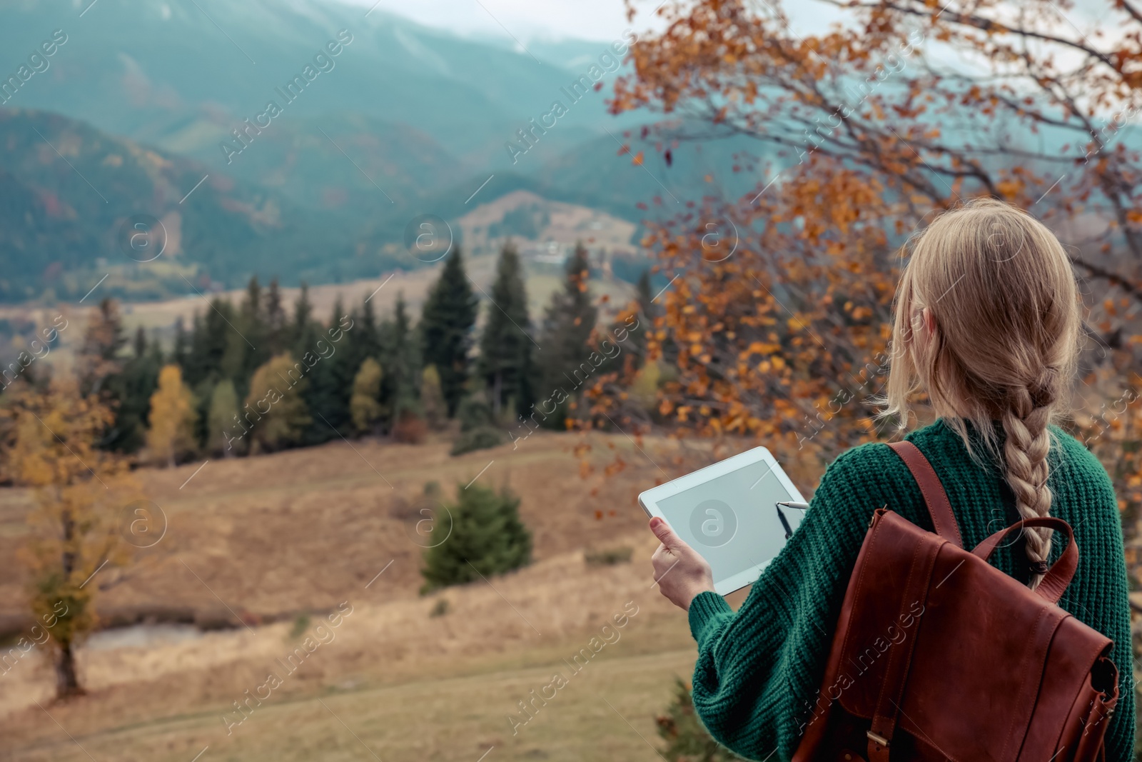 Photo of Young woman drawing on tablet in mountains, back view. Space for text