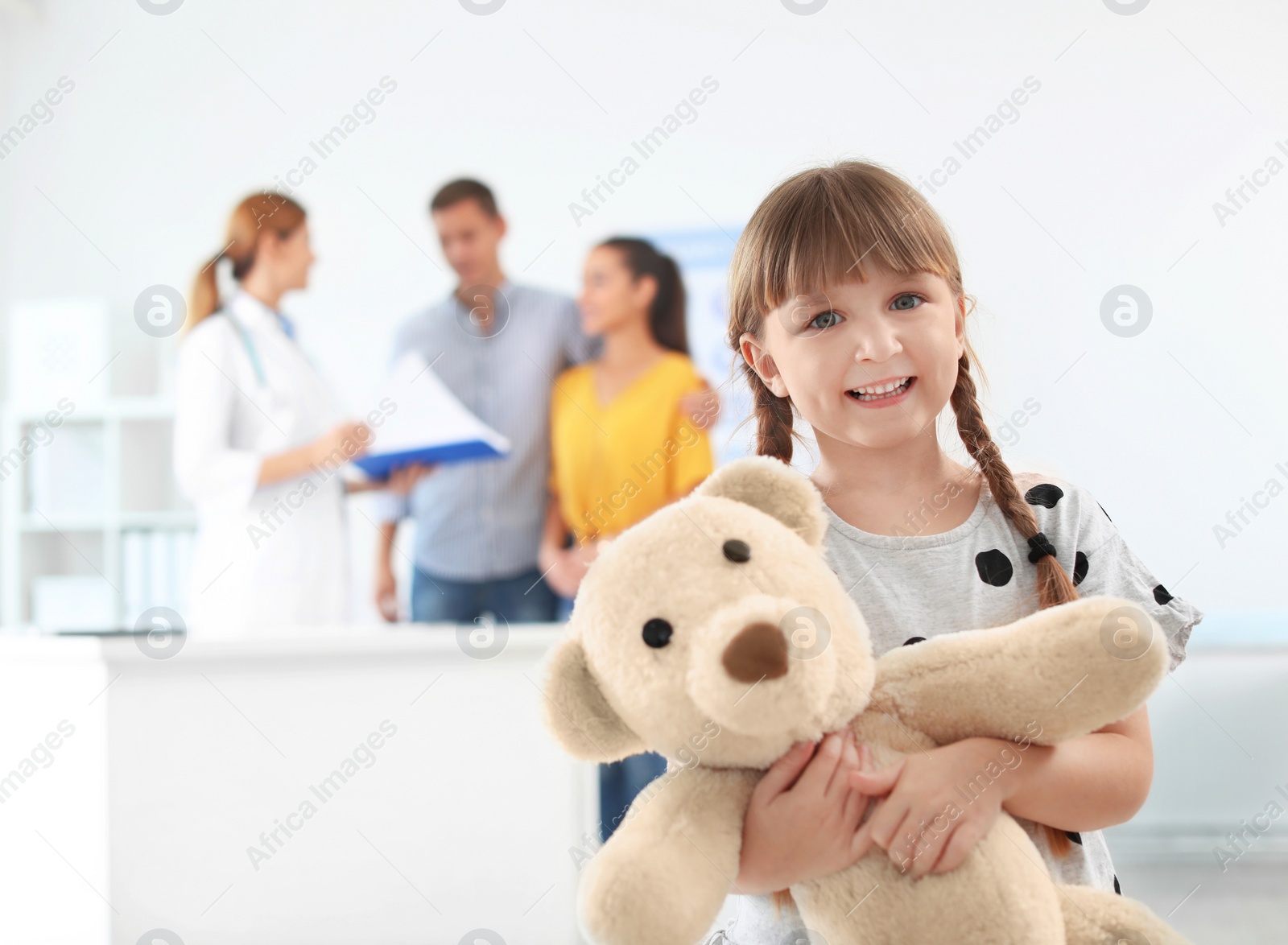 Photo of Little girl with parents visiting children's doctor in hospital