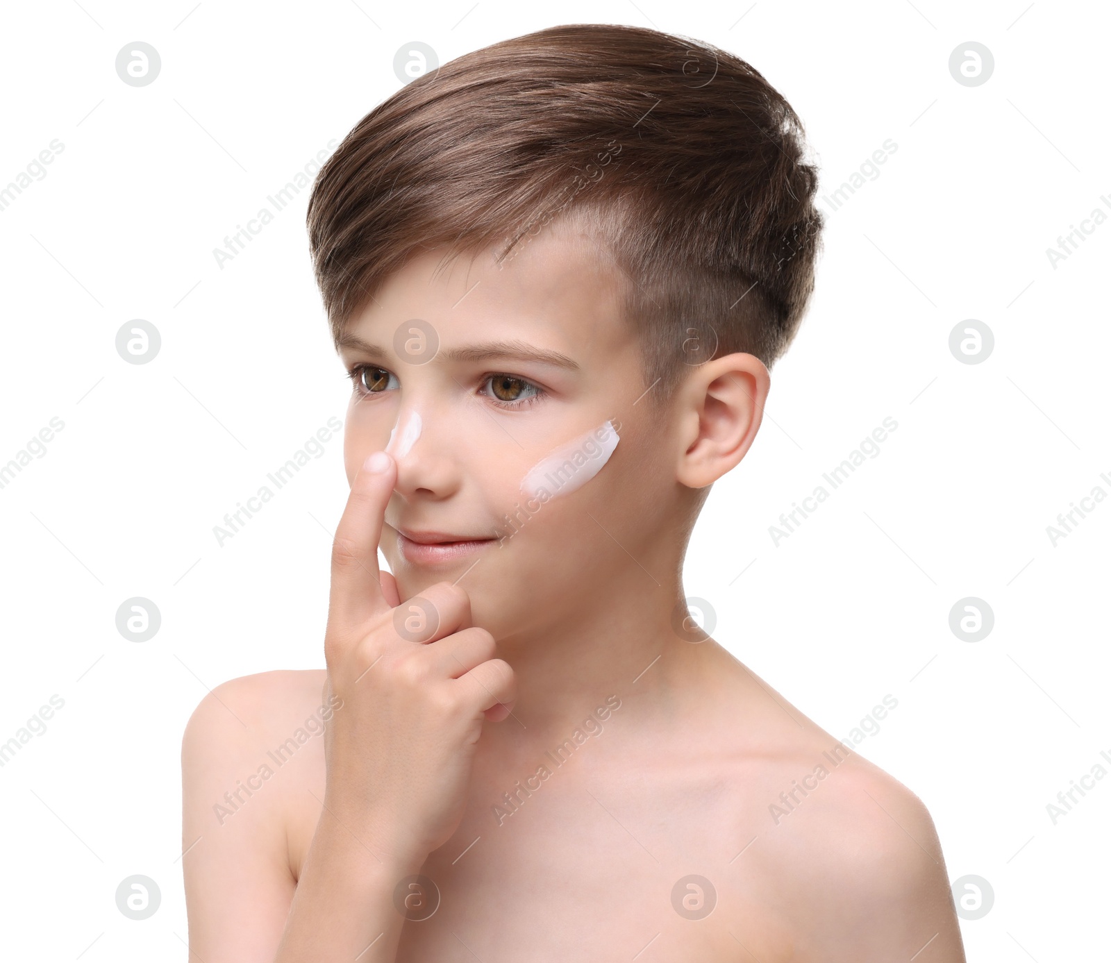Photo of Smiling boy applying sun protection cream onto his face against white background