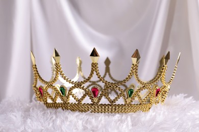 Photo of Beautiful golden crown with gems on white soft cloth