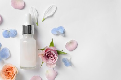 Photo of Bottle of cosmetic serum, beautiful roses and flower petals on white background, flat lay. Space for text