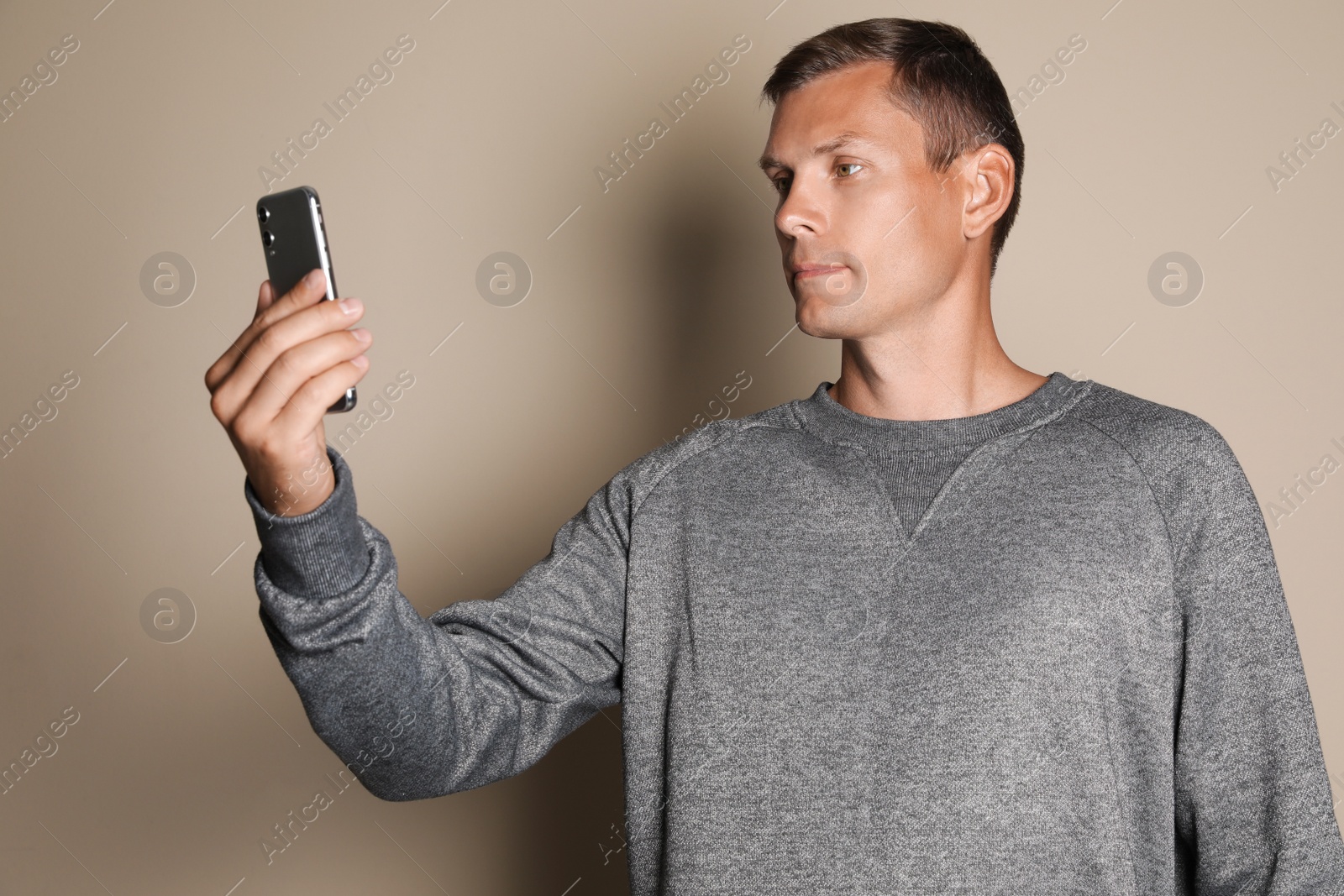 Photo of Man unlocking smartphone with facial scanner on beige background. Biometric verification