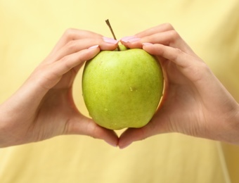 Photo of Woman holding fresh green apple indoors, closeup