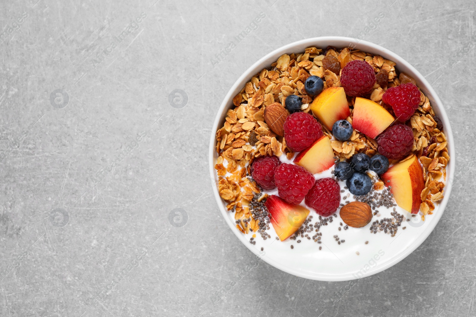 Photo of Healthy homemade granola with yogurt on grey table, top view. Space for text