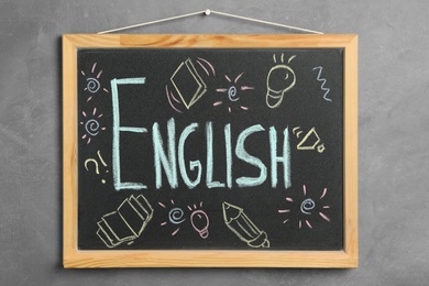 Photo of Blackboard with word English hanging on grey wall