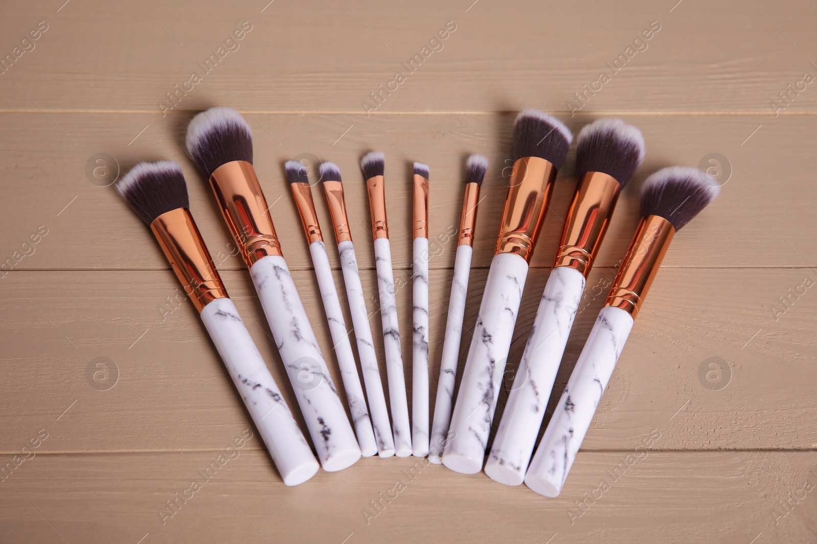 Photo of Set of professional makeup brushes on wooden background, above view