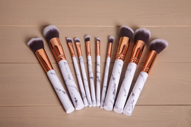 Set of professional makeup brushes on wooden background, above view