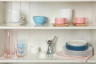 Photo of White shelving unit with set of dishware