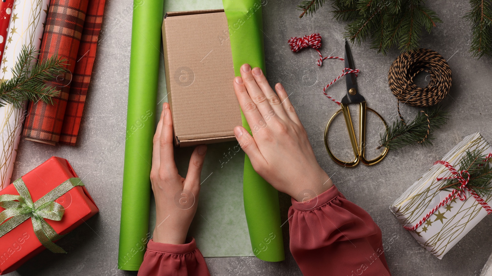 Photo of Woman Christmas gift at grey stone table, top view