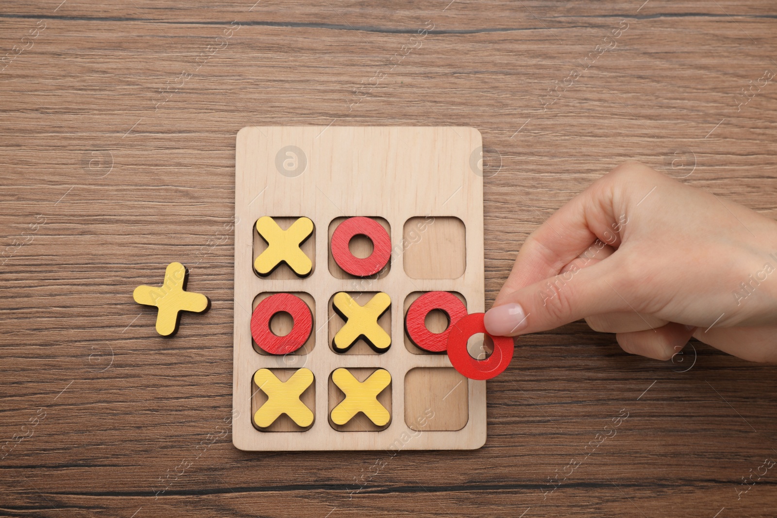 Photo of Woman playing tic tac toe game at wooden table, top view