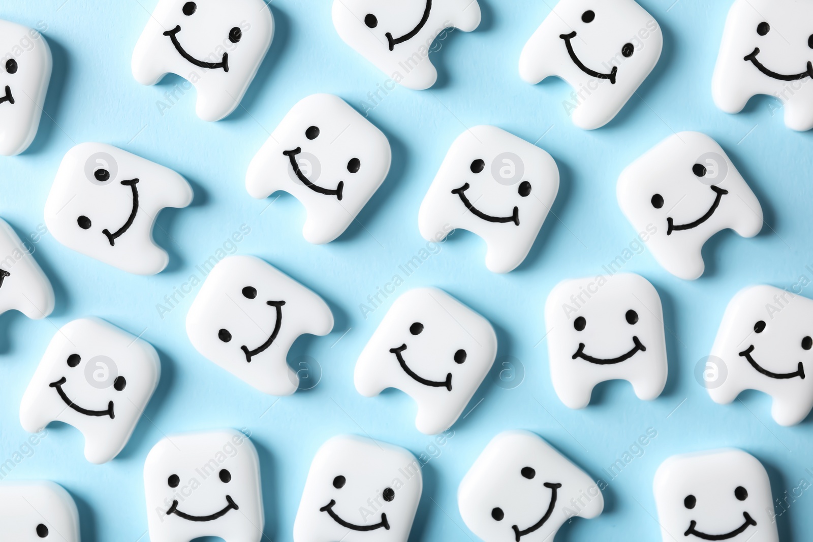 Photo of Many small plastic teeth with cute faces on color background, top view