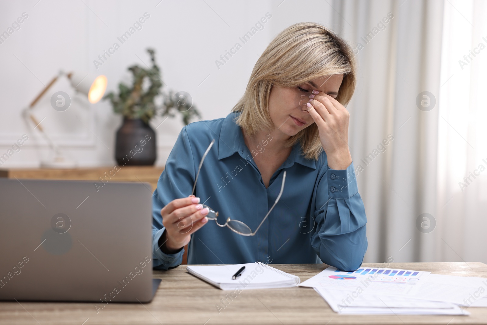 Photo of Overwhelmed woman with glasses sitting at table in office