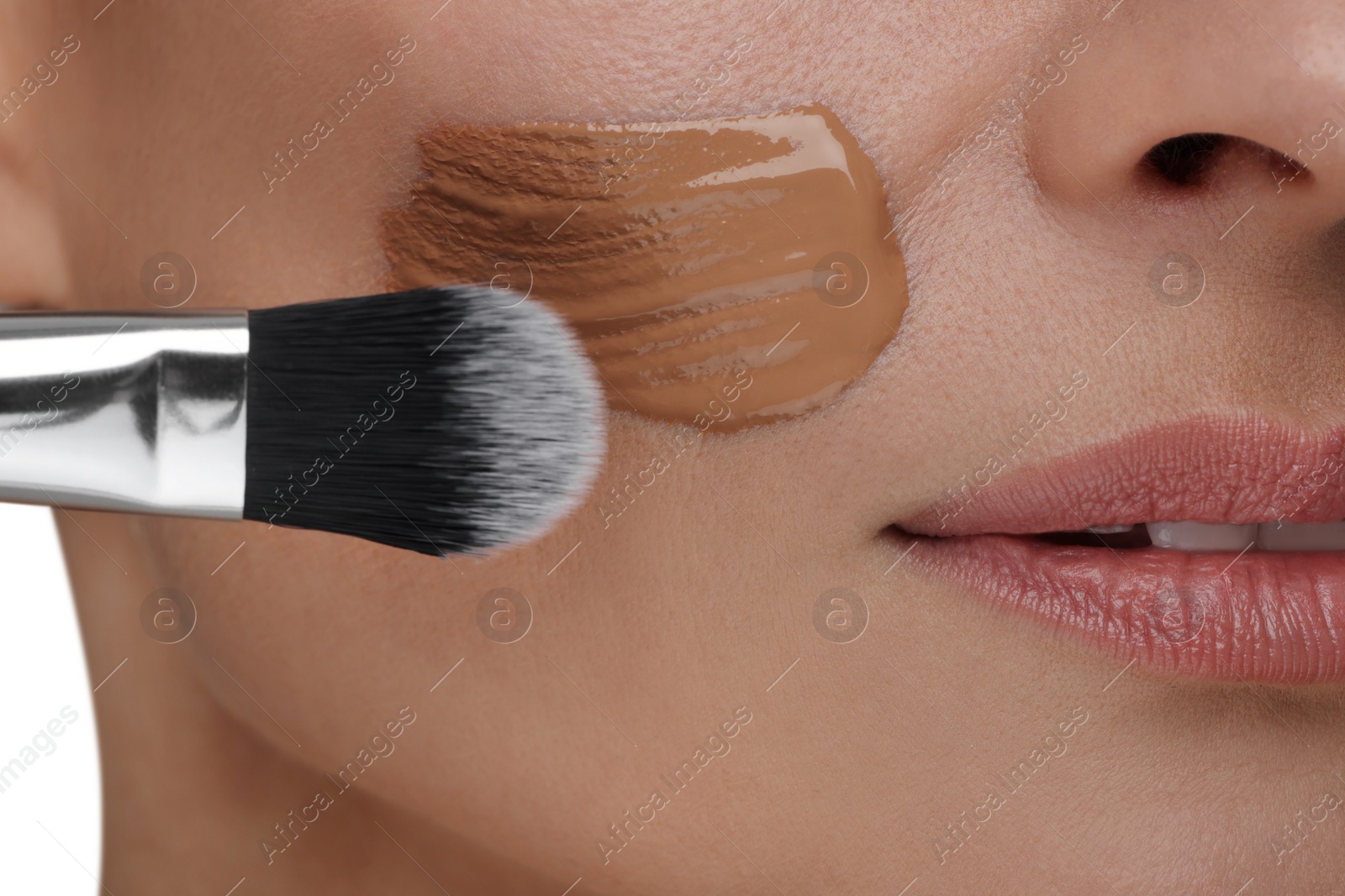 Photo of Woman applying foundation on face with brush, closeup