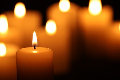 Photo of Burning candle on blurred background, closeup. Space for text