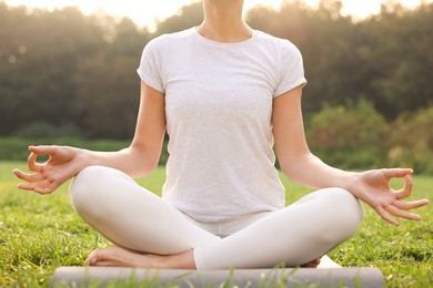 Photo of Woman practicing yoga on mat outdoors, closeup. Lotus pose