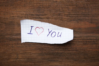 Photo of Sheet of paper with words I LOVE YOU on wooden table, top view
