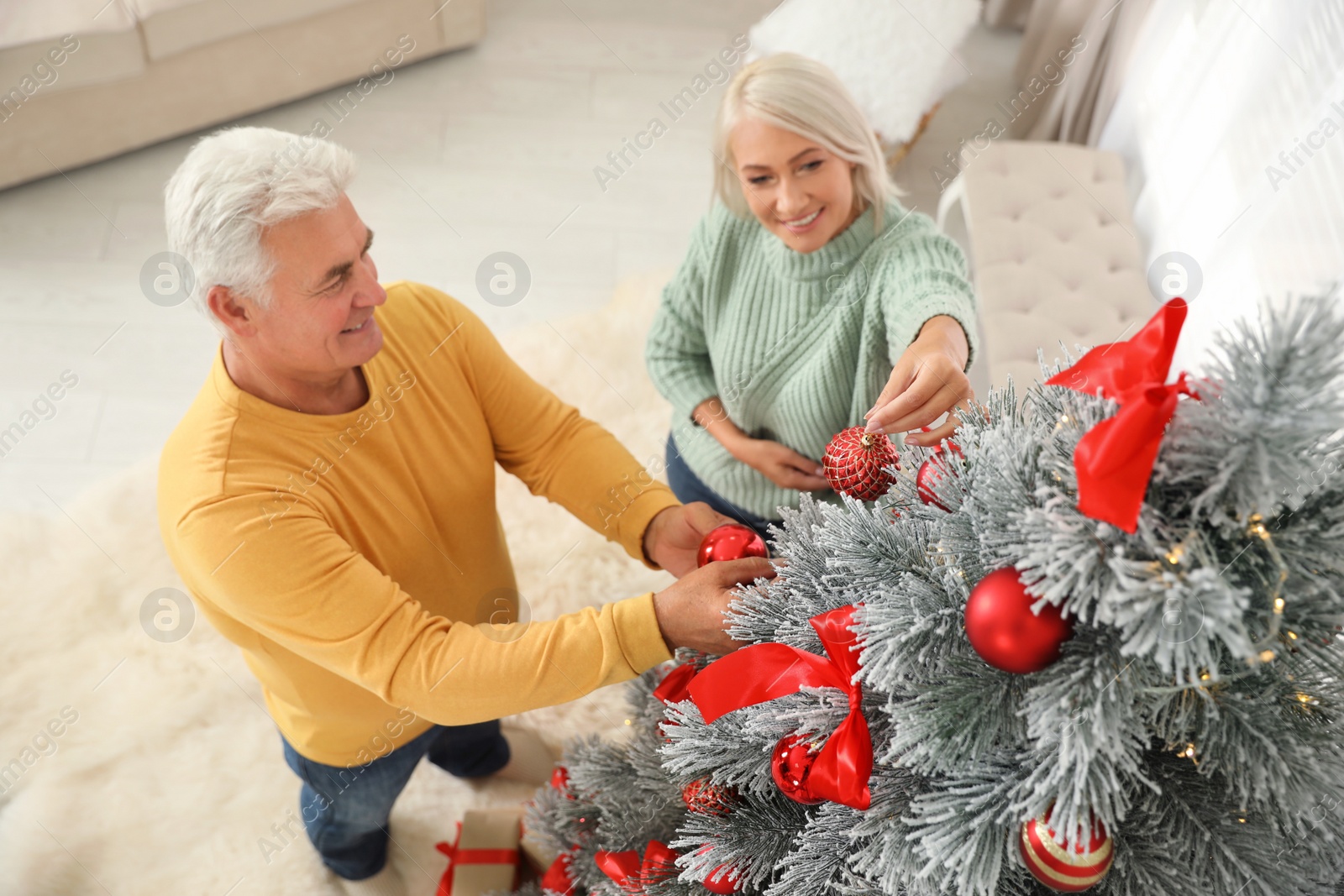 Photo of Happy mature couple decorating Christmas tree at home, above view