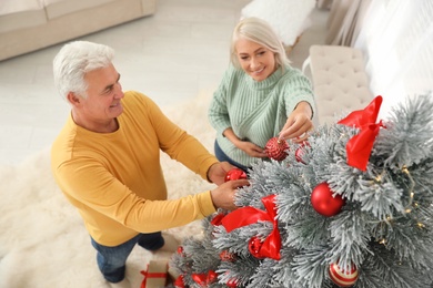 Photo of Happy mature couple decorating Christmas tree at home, above view