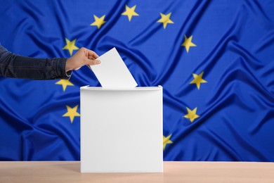 Image of Woman putting her vote into ballot box against flag of Europe, closeup