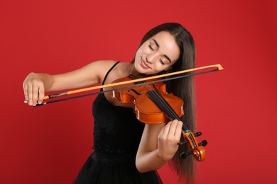 Beautiful woman playing violin on red background