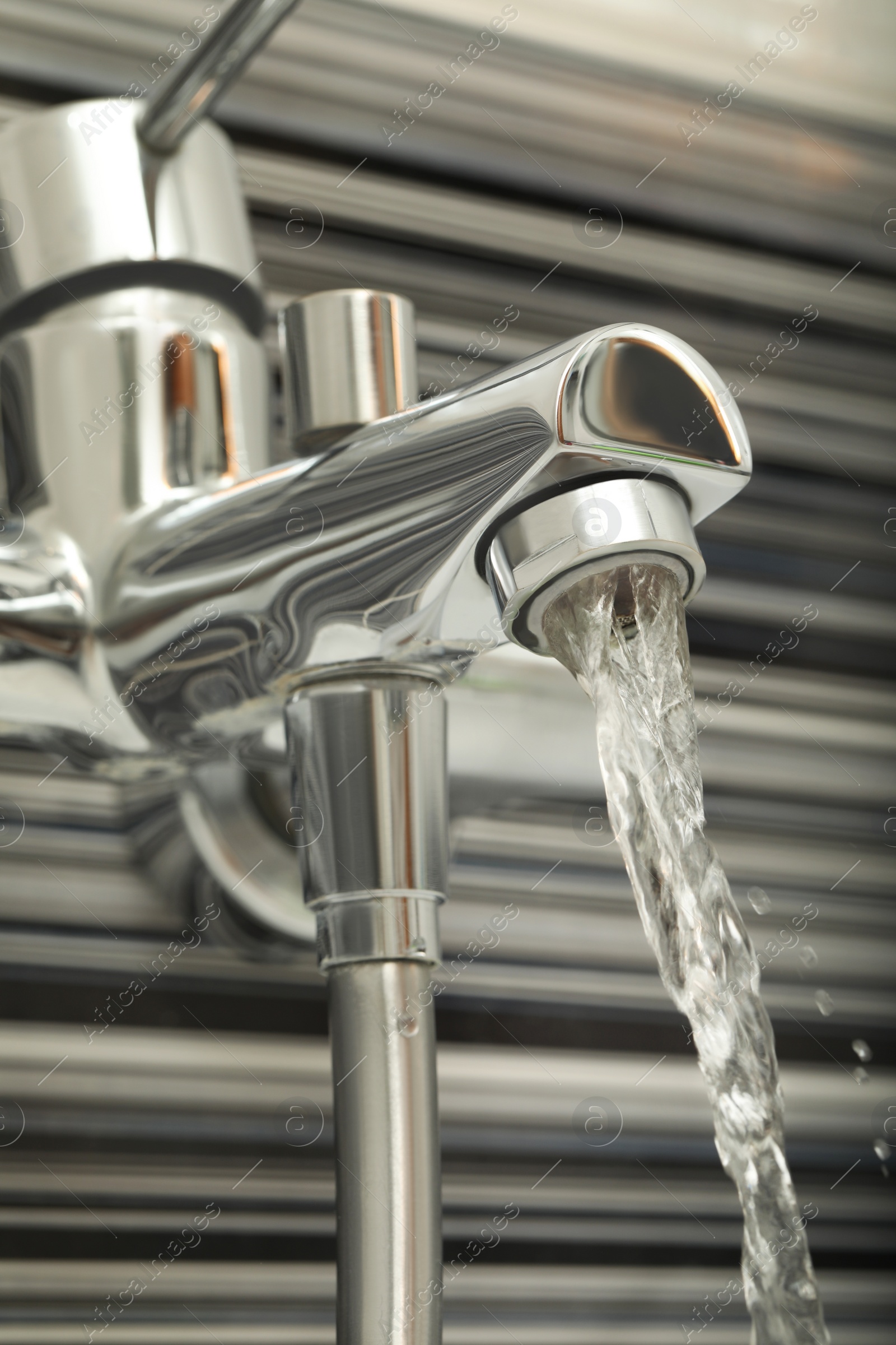 Photo of Water flowing from bath tap installed on black and white wall