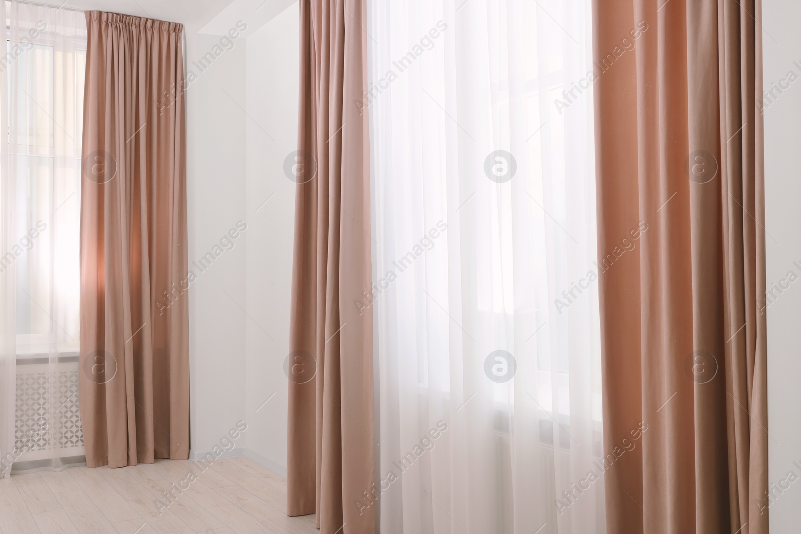 Photo of Elegant window curtains and white tulle indoors. Interior design