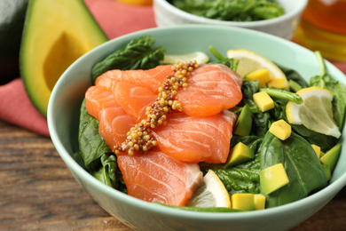 Photo of Delicious fresh salmon with spinach, avocado and lemon in bowl, closeup