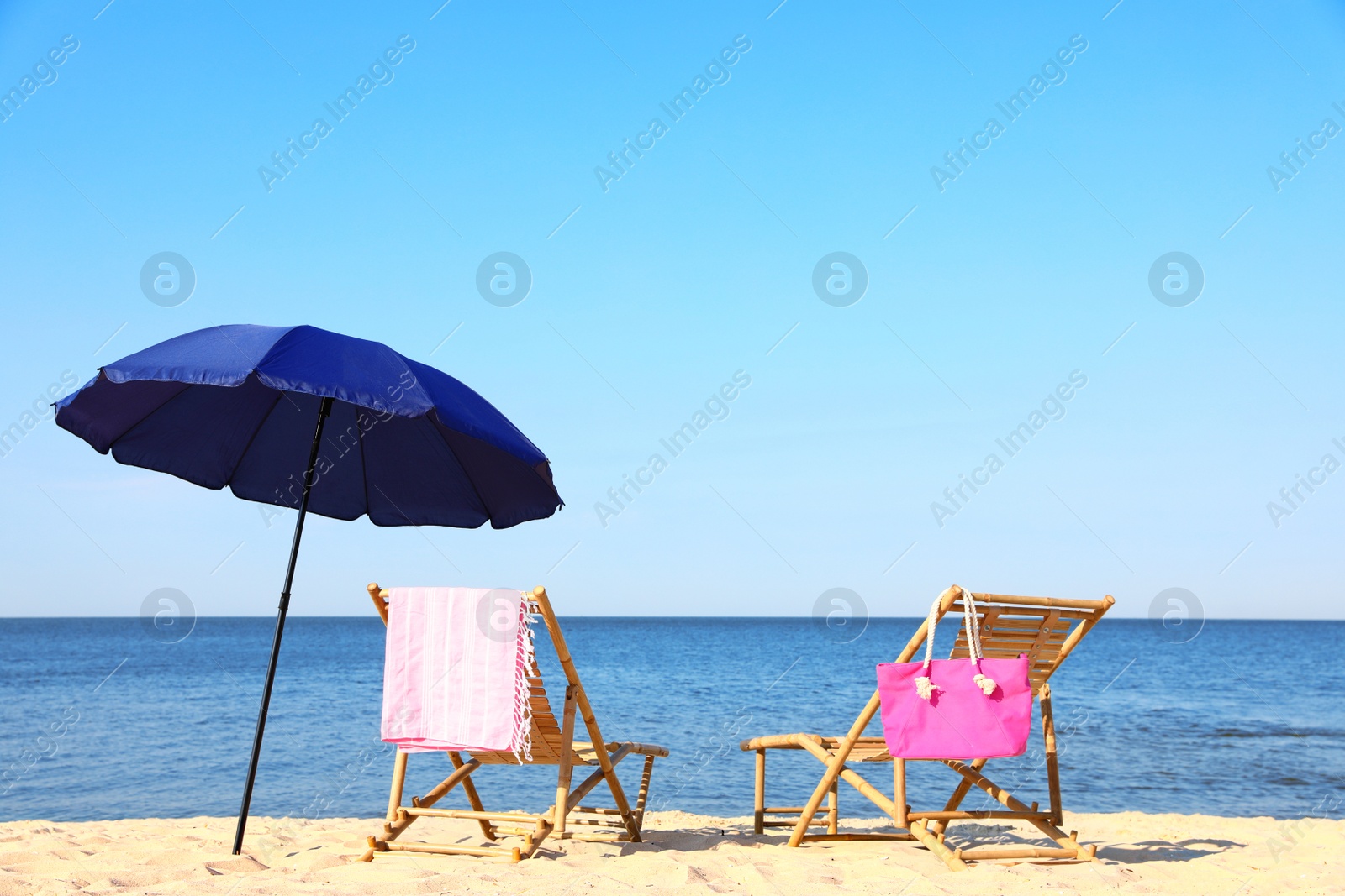 Photo of Empty wooden sunbeds and beach accessories on sandy shore