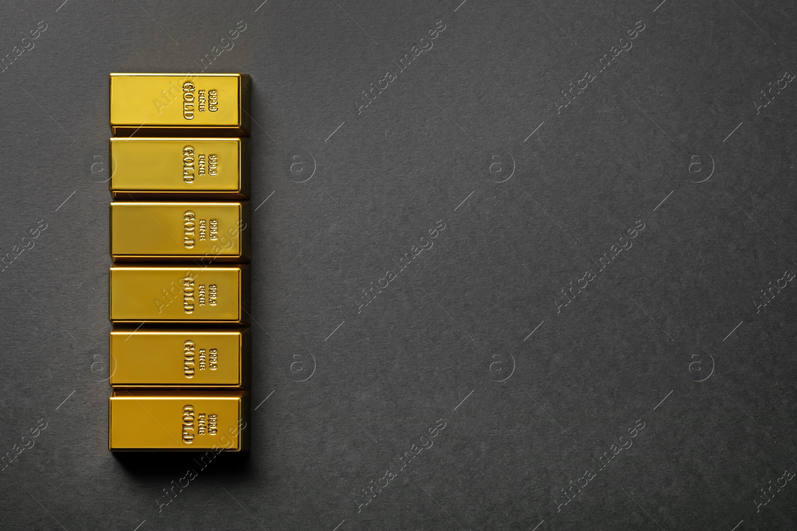 Photo of Many shiny gold bars on black background, flat lay. Space for text